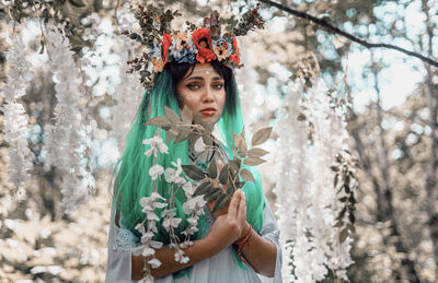 Portrait of woman standing by flower tree