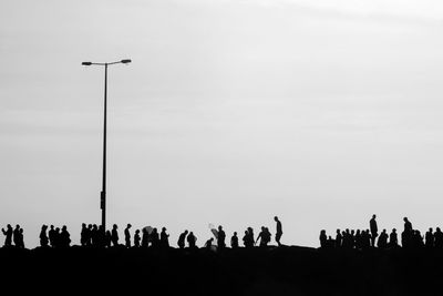 Silhouette people on street against sky