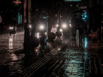 People walking on wet street during rainy season at night