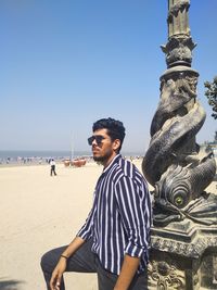 Full length of young man statue at beach against clear sky waiting for something