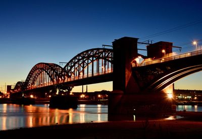 Bridge over river against clear blue sky at night