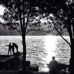 Silhouette of people sitting on lakeshore