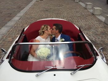 High angle view of happy young woman sitting on car