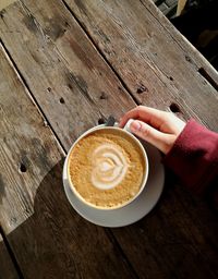 Close-up of woman holding coffee cup on table