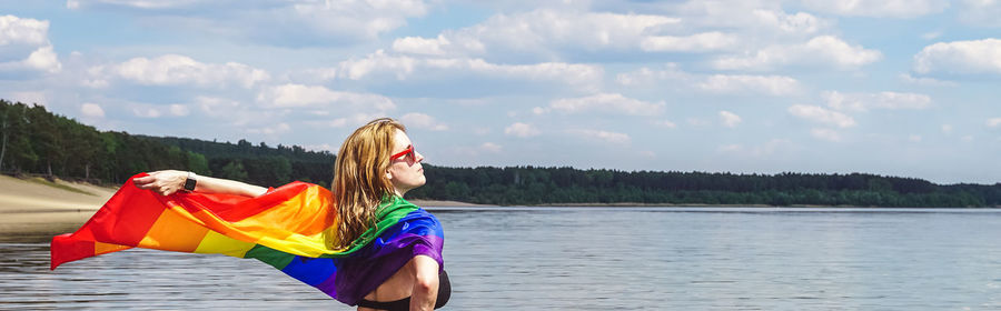 Woman with umbrella on lake against sky