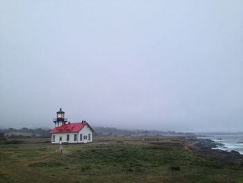 Lighthouse by sea against sky