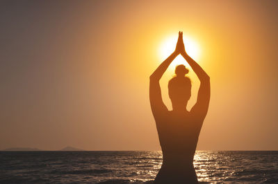 Rear view, silhouette of a woman holding the sun. a girl raising her hands, praying for god's