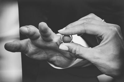 Cropped image of bride exchanging ring with groom during wedding