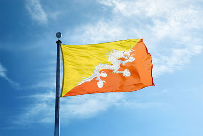 Low angle view of flag against yellow sky