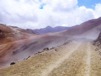 Panoramic view of desert against cloudy sky