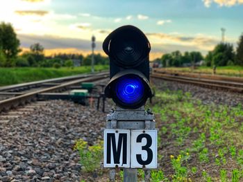 Information sign on railroad track against sky during sunset