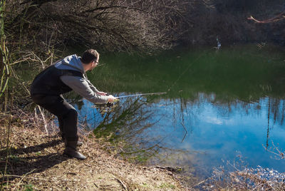 Side view of man standing by lake in forest