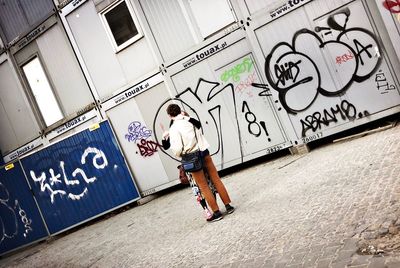 Man standing by graffiti on wall