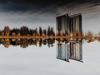 Deck chairs by lake against sky during sunset