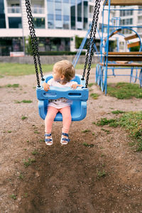 Girl sitting on swing at playground