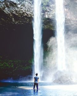 Rear view of man looking waterfall