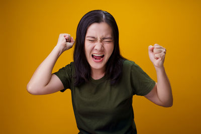 Young woman standing against yellow background