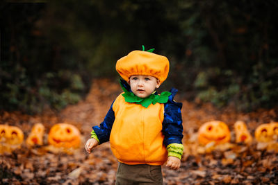 Full length of boy standing by pumpkin