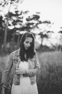 Young woman standing on grassy field against sky