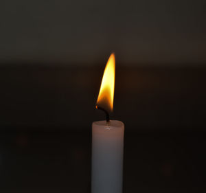 Close-up of lit candle in darkroom