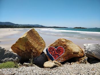 Love life text on stone at beach against sky