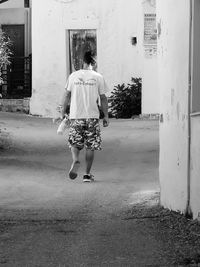 Rear view of woman walking on street against building