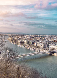 Aerial view of bridge over river in city against cloudy sky