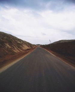 Road amidst land against sky