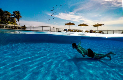 Man swimming in pool against sea