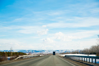 Road leading towards city against sky