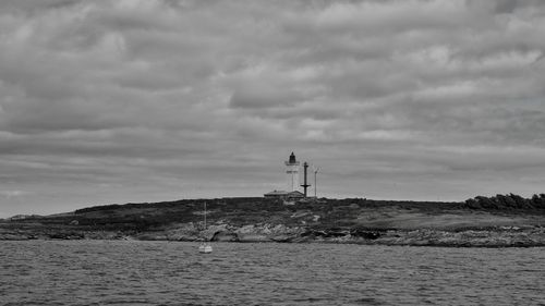 Lighthouse by sea against sky