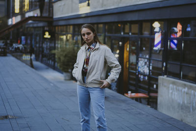 Portrait of young man standing on street in city