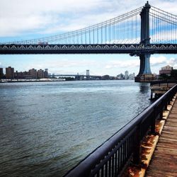 Bridge over river against cloudy sky