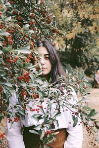 Portrait of young woman standing against plants