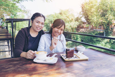 Happy friends sitting on table