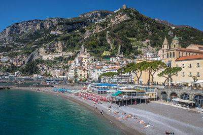 View of houses on mountain by sea against clear blue sky during sunny day