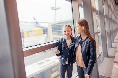 Sisters standing by window at airport
