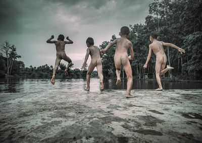 Group of people walking on wet shore against sky