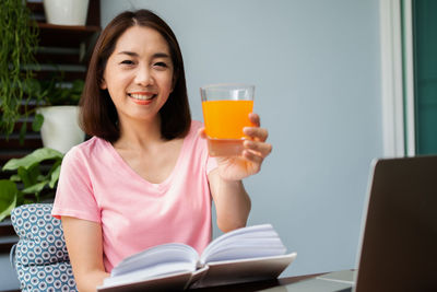 Portrait of smiling young woman sitting on table