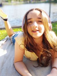 Portrait of smiling girl listening music while lying in park