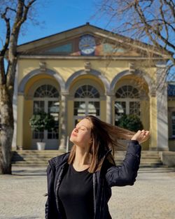 Mid adult woman standing outside temple against building