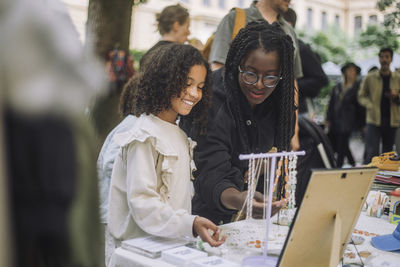 Mother and daughter buying jewelry while shopping at flea market