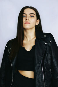 Portrait of beautiful young woman standing against wall