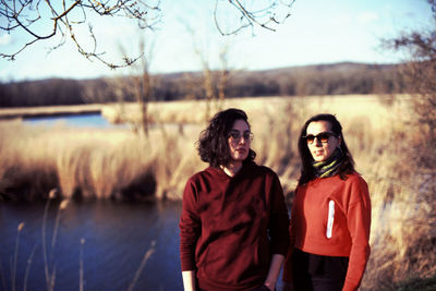 Portrait of female friends standing at lakeshore