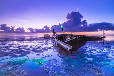 Boat moored on sea against sky during sunset