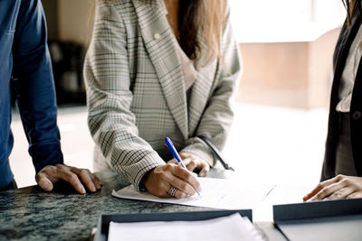 Midsection of couple signing contract with real estate agent in kitchen