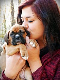 Close-up of woman kissing puppy outdoors