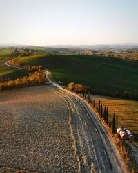 Road amidst field against clear sky