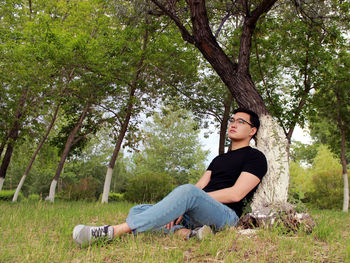 Young man sitting by the tree in a park