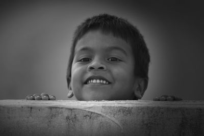 Close-up portrait of boy smiling by retaining wall